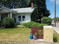 White bungalow and lawn with a historic marker at the bottom right.